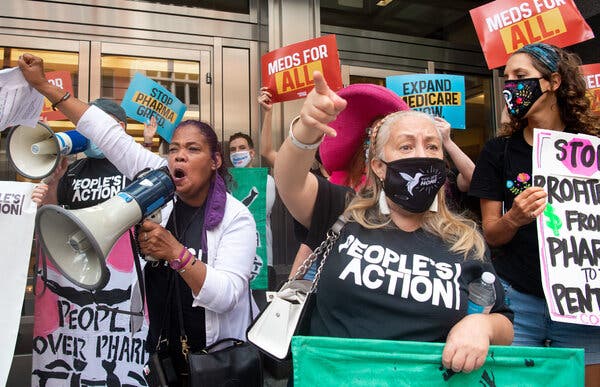 People wearing signs that read things like "Meds for All" and "People Over Pharma" protest outside the headquarters of the Pharmaceutical Research and Manufacturers of America in Washington.